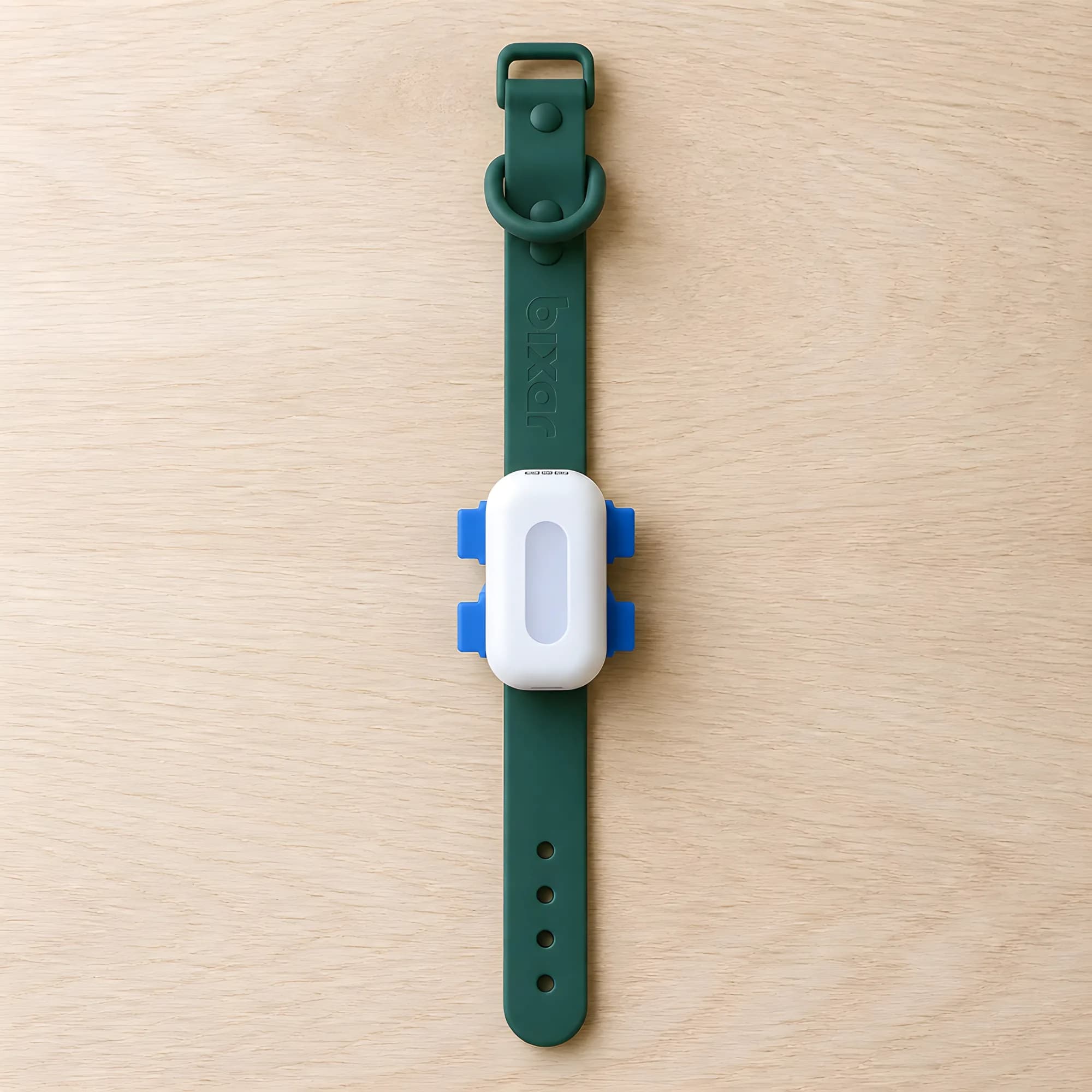 Le traceur Viva GPS sur son collier vert, posé sur du bois clair