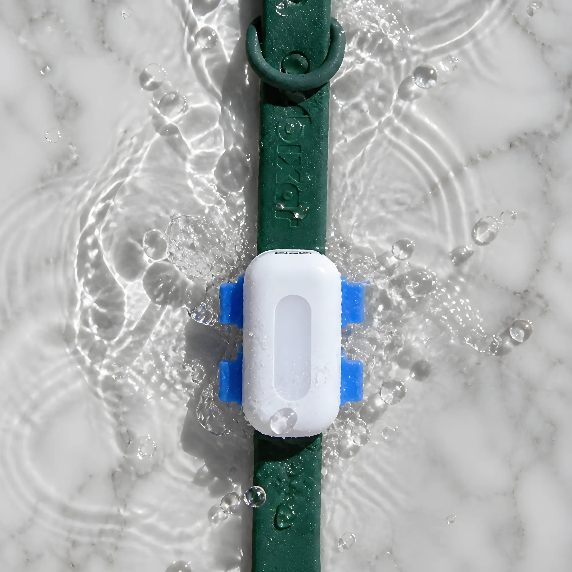 Le traceur Viva sur un collier vert, éclaboussé d'eau sur du marbre